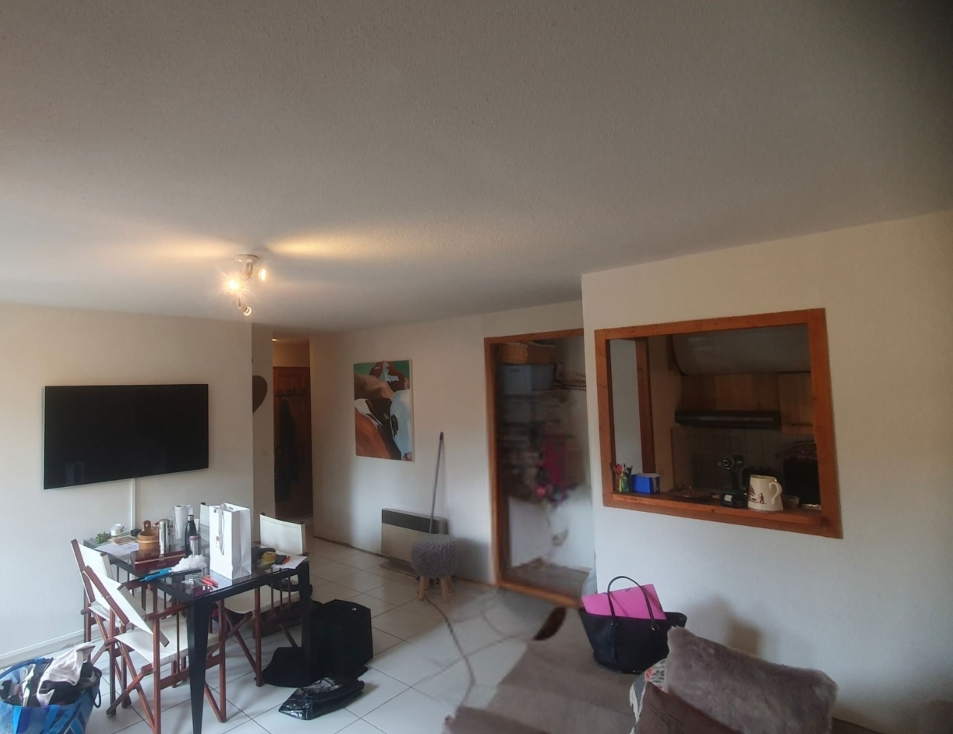 avant rénovation pièce Renov’Var (1) Intérieur d'un appartement en rénovation avec murs blancs, carrelage au sol, bureau noir, miroir encadré bois et porte