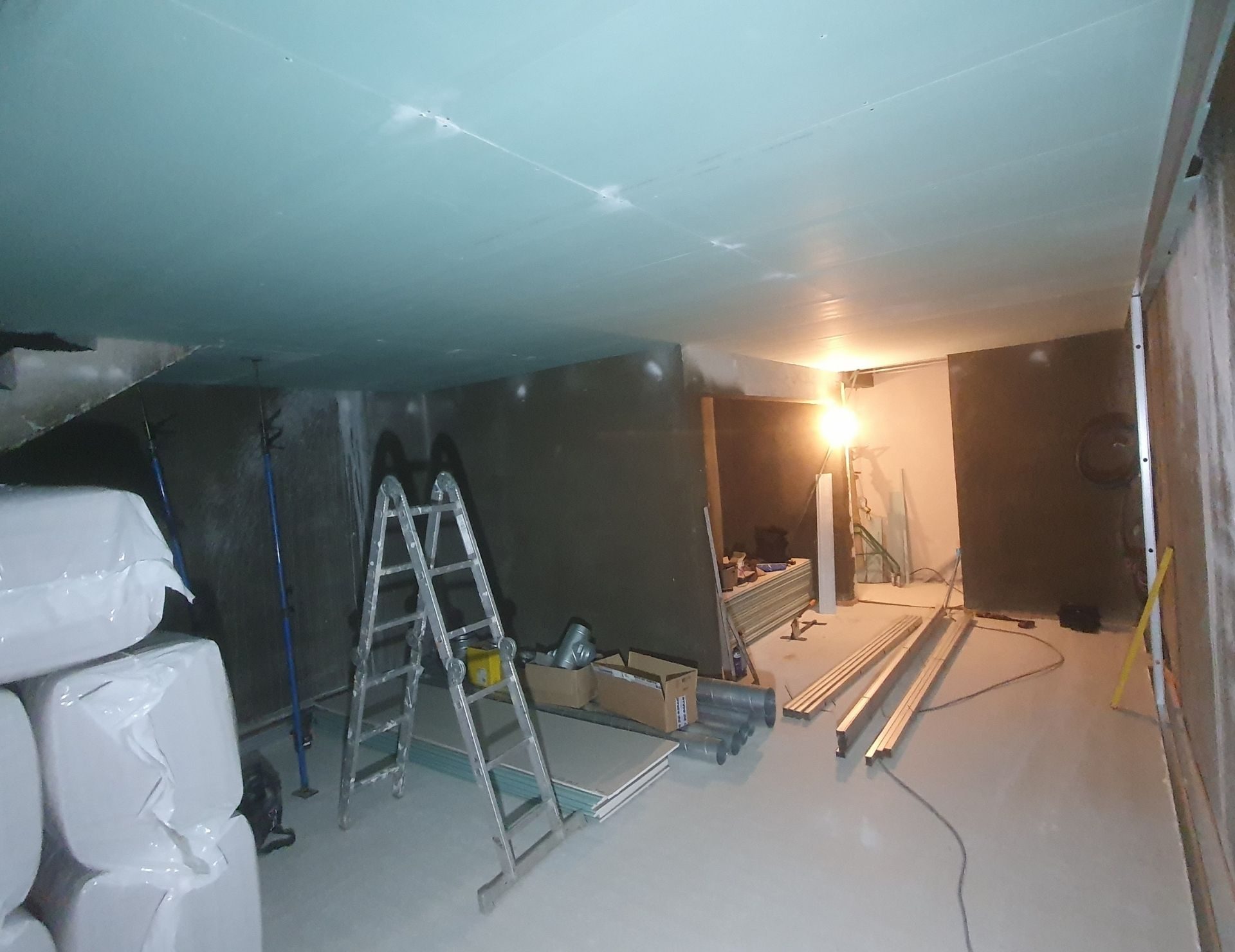 avant rénovation sous-sol Renov’Var Chantier de rénovation intérieure avec cloisons en construction, ladder, matériaux et éclairage de travail