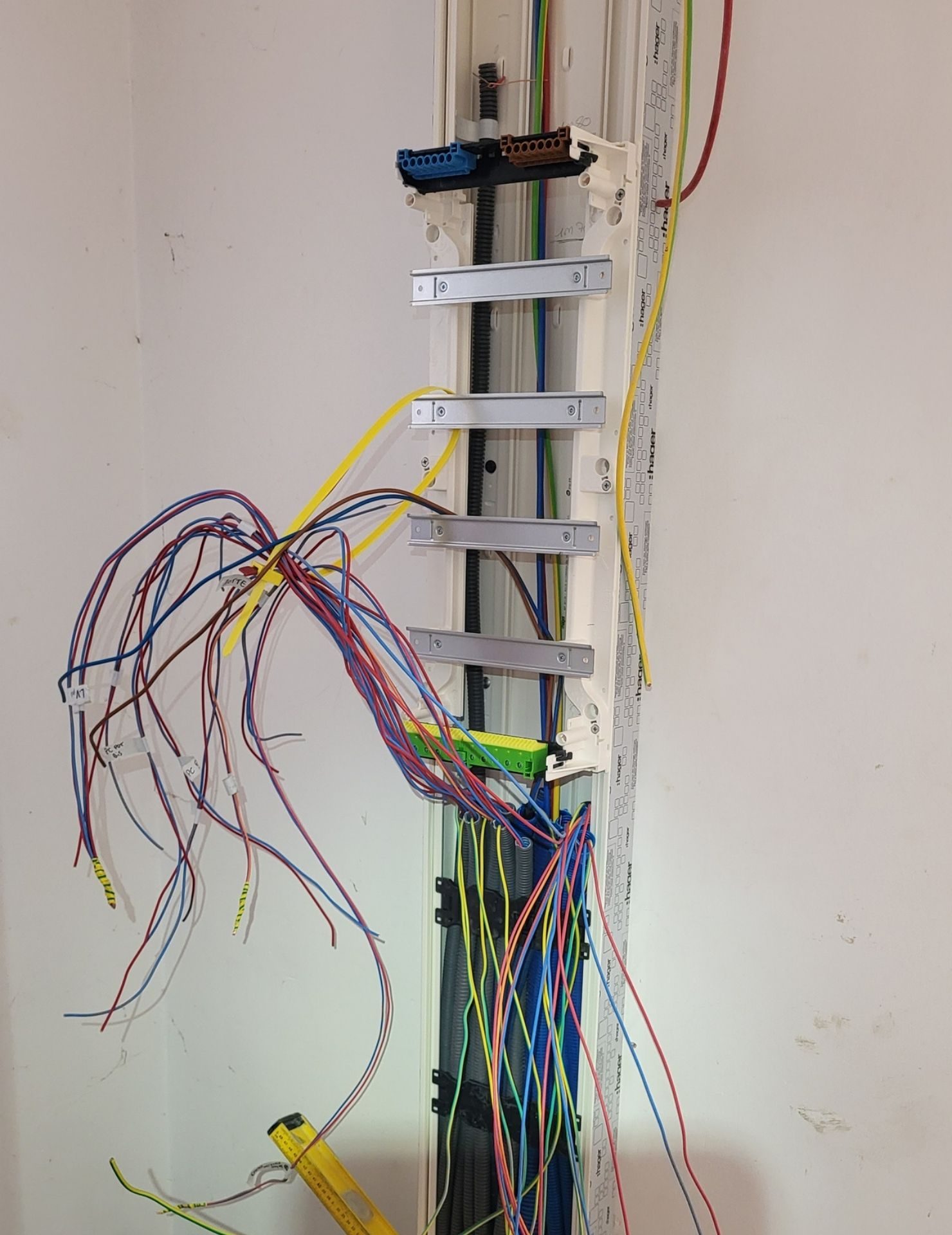 avant tableau électrique Renov’Var Installation électrique en cours avec câbles multicolores, rails de fixation métalliques, bornier bleu et schéma de